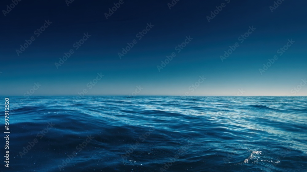 Obraz premium Serene ocean view showcases deep blue water meeting the horizon under a clear sky, perfect for travel, nature, or relaxation themed projects and designs.