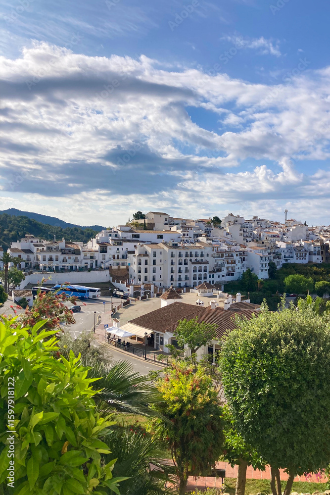 Fototapeta premium FRIGILIANA, SPAIN - MAY 10, 2025: A peaceful walk through the charming narrow streets, surrounded by whitewashed houses and colorful flowers in Frigiliana, Spain