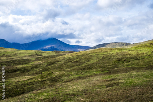 Scenic Rolling Hills and Distant Mountains under Cloudy Sky