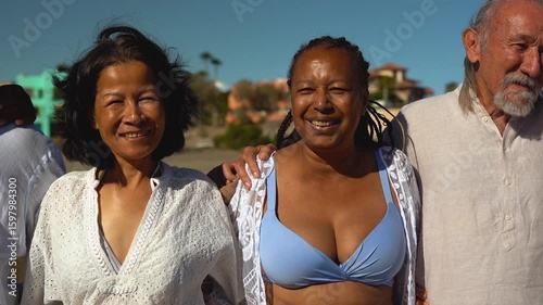 Happy senior people hugging each other on the beach during summer vacation - Travel and elderly friends concept	