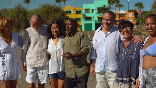 Happy senior people hugging each other on the beach during summer vacation - Travel and elderly friends concept	