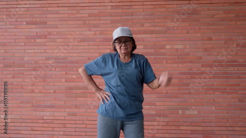 A senior woman stays active and energetic by exercising through aerobic dance. Positive emotion reflects a healthy lifestyle, embracing movement and workout routines to strong in her elderly years