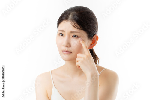 肌の悩みを気にする若い女性の表情（白背景）