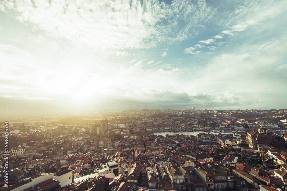 Obraz premium Sunlight illuminates the sprawling rooftops of Porto. The Douro River winds through the urban landscape, showcasing iconic landmarks and attracting diverse travelers