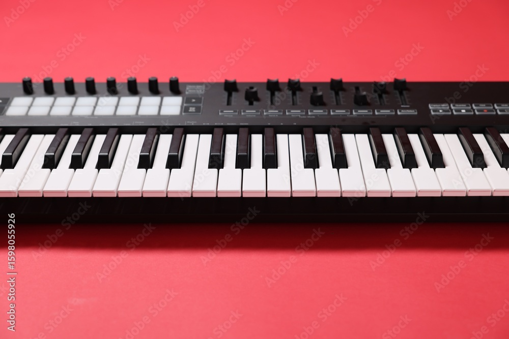 Fototapeta premium One portable MIDI keyboard on red background, closeup