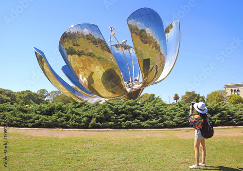 Female Visitor Shooting Photos of The Floralis Generica, a flower sculpture made of steel and aluminum, located on the Plaza de las Naciones Unidas in Buenos Aires, Argentina, South America