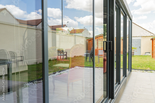 Gros plan sur une véranda moderne réalisée par une entreprise spécialisée, avec poignées et encadrement extérieur en PVC gris anthracite, mettant en valeur les finitions et le savoir-faire professionn