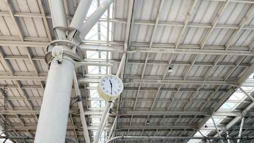 A clock to see the time while waiting for the train. Scene from a Indonesia train station with details from a steel construction. Concept of transportation, traffic, rush hours, time and etc.