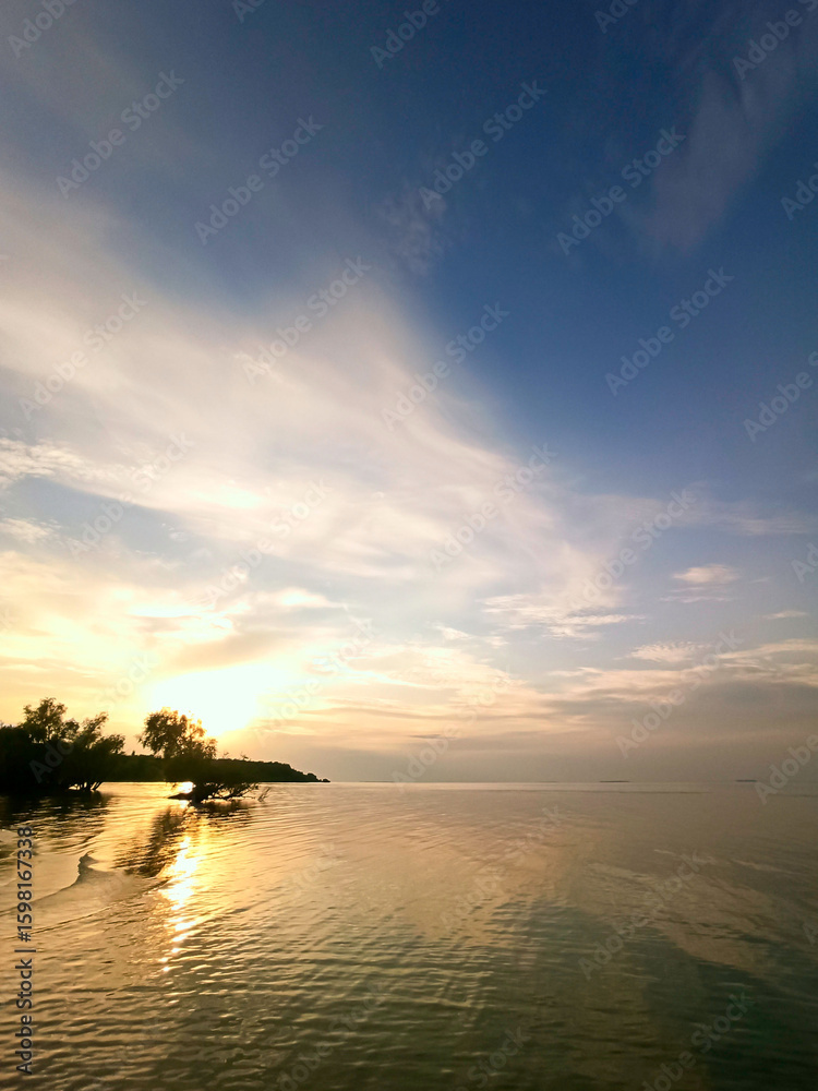 Fototapeta premium Sunset at sea. Vertical seascape with view of shore, water surface and sky at sunset. Concept of calm and harmony. Inspiring natural view for meditation.