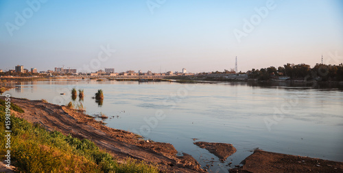 Tableau sur toile View of the Tigris River at sunset in Baghdad showcasing lush banks and city sky