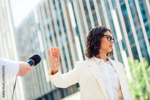 Photography Confident businesswoman in white suit declining interview microphone outdoors in