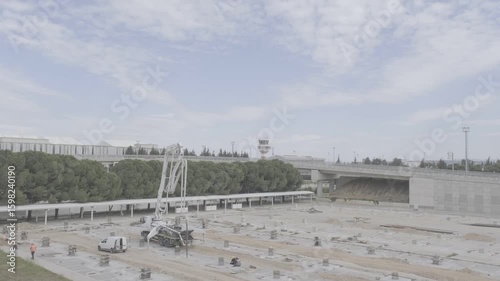 Wide shot of construction site at an airport, with concrete pump truck, workers, and foundation works visible. Control tower in background. Captured in Turkey for infrastructure and construction theme