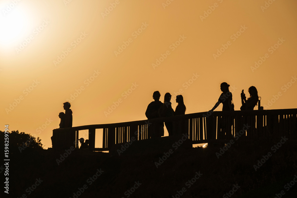 Fototapeta premium Tourists watching and photographing the sunset in the Algarve, Portugal.