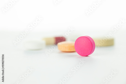 Fotografia A single pink round tablet in selective focus