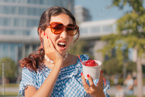 Photos Young woman is holding a cup of ice cream and experiencing a sudden toothache du