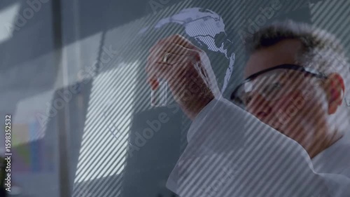 Senior scientist inspecting test tube against light activating technology interface forming globe