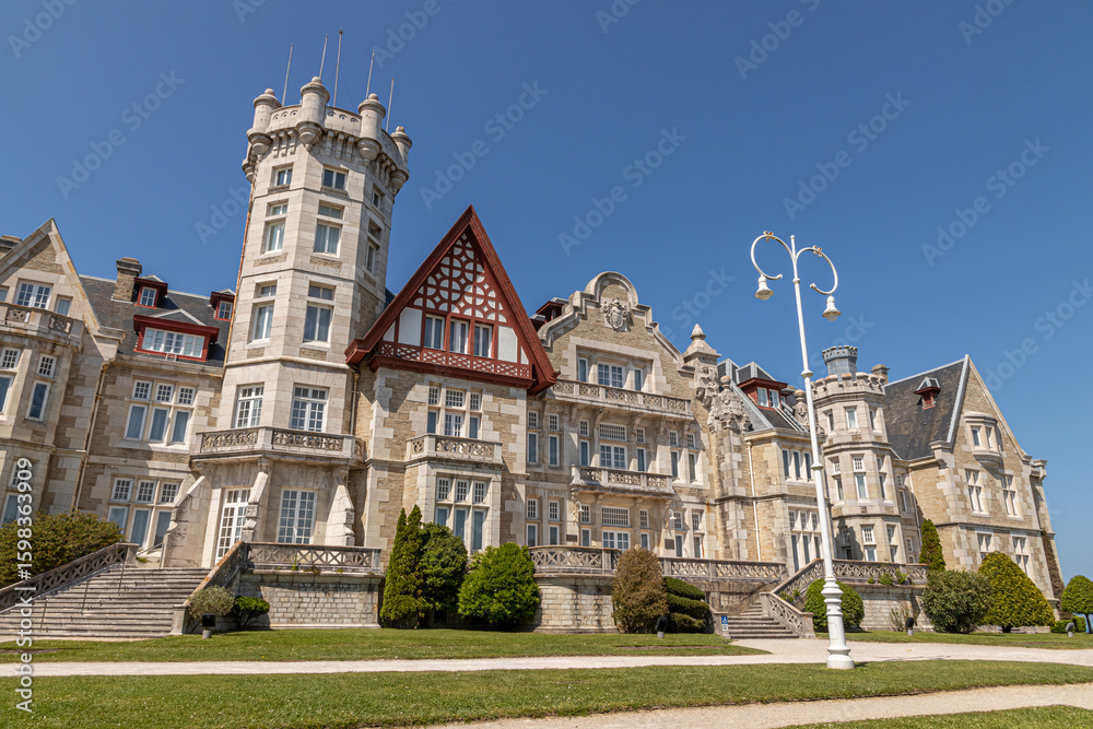 Fototapeta premium Santander, Spain. Spring view of the Palacio de la Magdalena with its grand facade, lush green lawn, and clear blue sky, once the royal summer residence of the Spanish monarchy