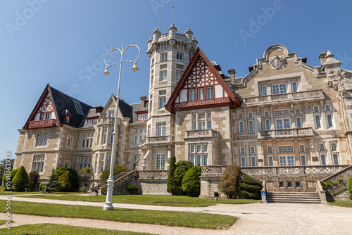 Santander, Spain. Spring view of the Palacio de la Magdalena with its grand facade, lush green lawn, and clear blue sky, once the royal summer residence of the Spanish monarchy
