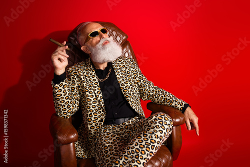 Foto Eccentric elderly gentleman in vibrant leopard suit with sunglass seated against