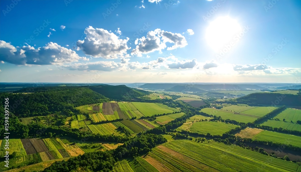 Naklejka premium High-angle view of rolling hills, fields, and forests under a vibrant blue sky