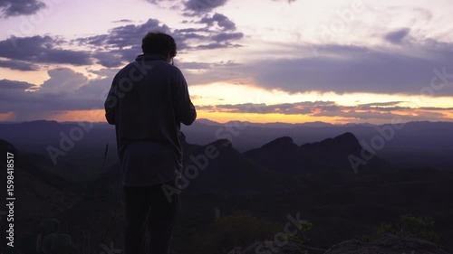 A man taking a picture at dusk from a scenic viewpoint