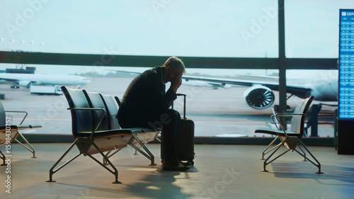 Canvastavla Stressed Business traveler sitting alone in airport lounge with head in hands, s
