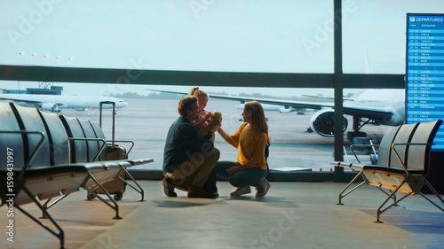 Принти на полотні Emotional family reunion at airport gate as parents kneel to hug their daughter, with airplane visible through large windows — capturing love, travel, and heartfelt moments of arrival or farewell