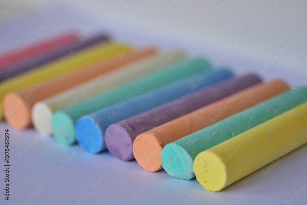 Fototapeta premium Side angle view of large pastel chalk sticks arranged in neat rows. Artistic texture and vibrant colors represent creative expression, school supplies, and children drawing tools.