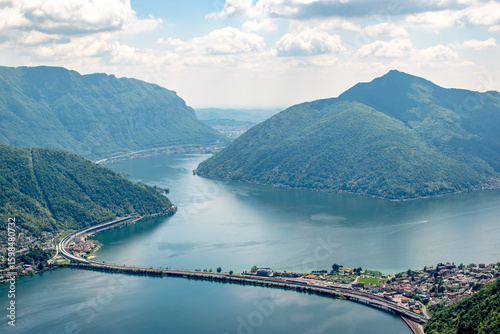 Aerial view of a lake surrounded by mountains with a bridge and town.