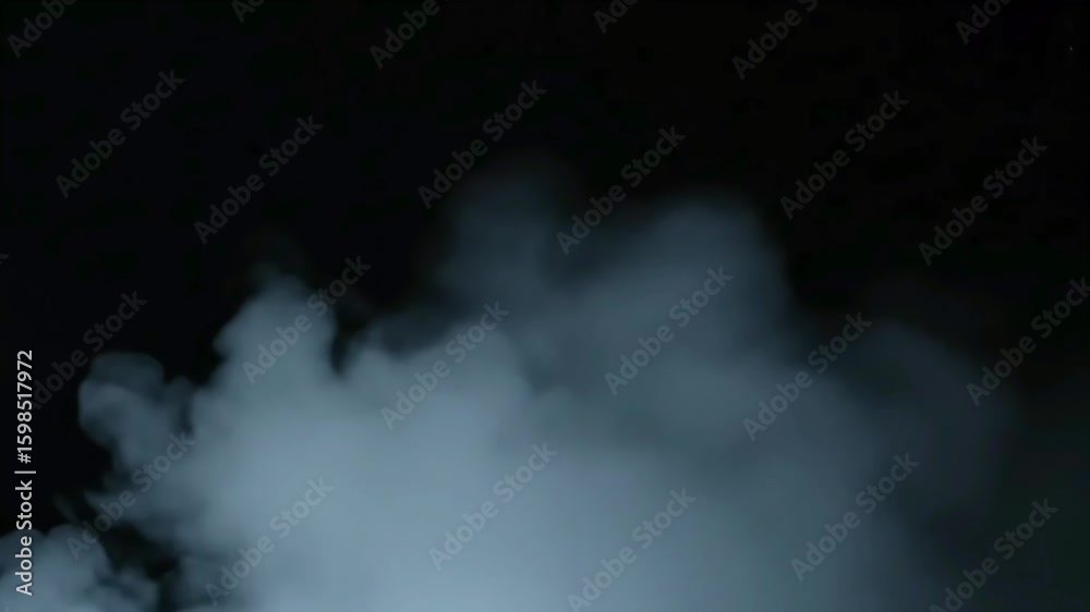 Realistic thick blue grey smoke billows on a dark black background creating a mysterious atmospheric cloud of fog and steam ideal for overlays and visual effect