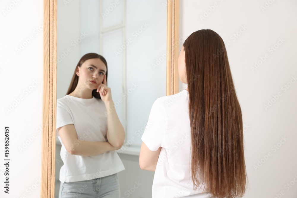 Fototapeta premium Beautiful young woman posing near mirror indoors
