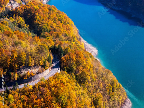 Scenic autumn road winding through vibrant fall foliage and mountains near a lake