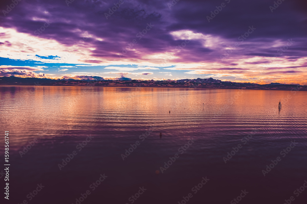 Fototapeta premium Calm lake at sunset with a purple-orange sky.
