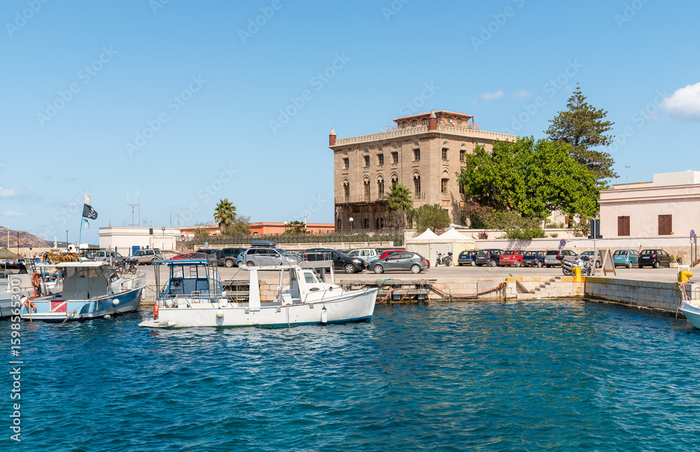 Naklejka premium Port of Favignana with boats and Palazzo Florio in the background, Egadi Islands, province of Trapany, Sicily, Italy