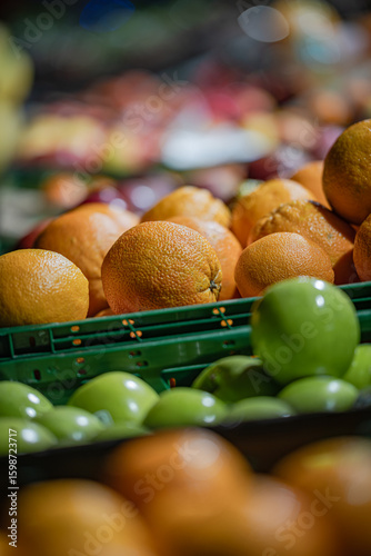 Close-up of green apples and oranges in plastic crates at fruit market