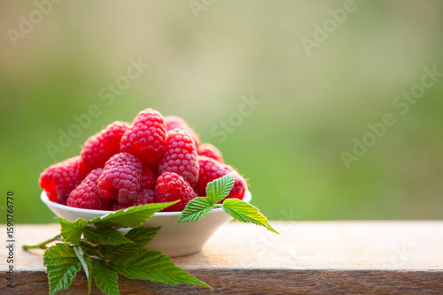 Bowl of fresh raspberries on rustic wood background, natural harvest.