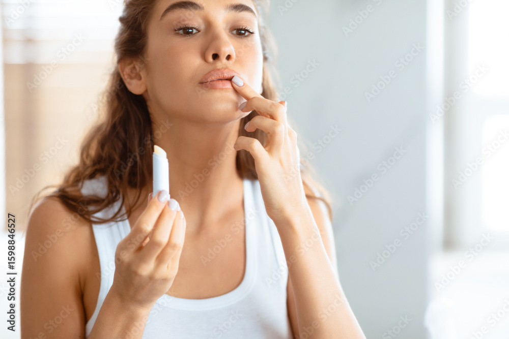 Young Lady Applying Lip Balm Moisturizing Skin Caring For Herself Standing In Modern Bathroom Indoors. Lips Skincare Concept, Beauty Routine. Cropped Shot, Selective Focus On Lipstick Young Lady Applying Lip Balm Moisturizing Skin Caring For Herself Standing In Modern Bathroom Indoors. Lips Skincare Concept, Beauty Routine. Cropped Shot, Selective Focus On Lipstick