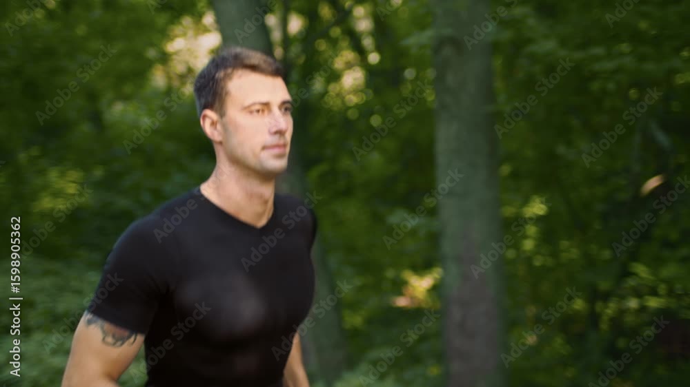 A young man is jogging outdoors in a lush green park, enjoying the warm summer day. He maintains a focused expression as he engages in his fitness routine, promoting a healthy lifestyle. A young man is jogging outdoors in a lush green park, enjoying the warm summer day. He maintains a focused expression as he engages in his fitness routine, promoting a healthy lifestyle.