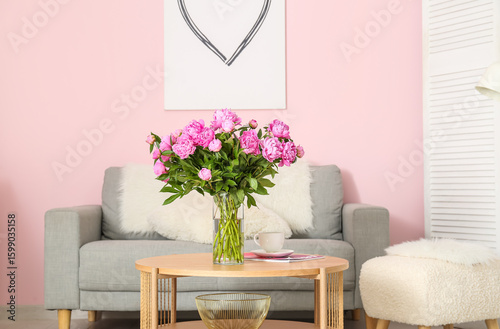 Vase of pink peonies on coffee table with couch in living room