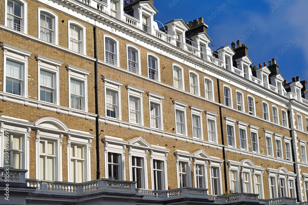 Fototapeta premium Yellow brick apartment buildings with white window frames and balustrade in London, England