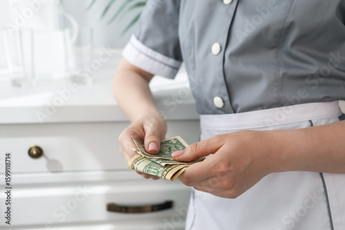 Cuadro en lienzo Chambermaid counting tips leaning chest of drawers in hotel room, closeup