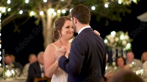 A newly married couple shares a tender first dance under twinkling lights, celebrating their love.