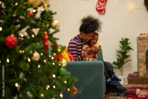 Fotografia An African American family gathers for a festive Christmas party, enjoying snacks, drinks, and laughter in their decorated living room