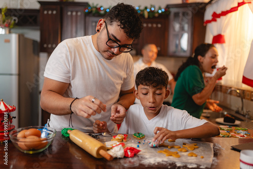 Latino teen and young man decorating Christmas cookies in festive kitchen