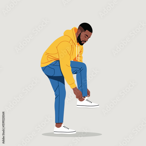 Man Tying Shoelace in Yellow Hoodie and Blue Jeans on Plain Background