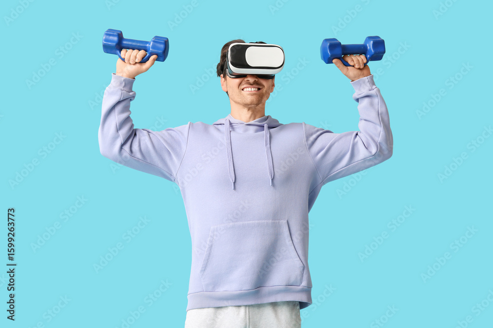 Sporty young man in VR glasses with dumbbells on blue background Sporty young man in VR glasses with dumbbells on blue background