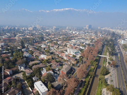 Aerial view of a modern city with tall buildings, traffic, and a canal running alongside a main avenue on a hazy day. Urban skyline and infrastructure from above.
