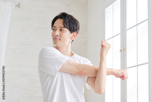Foto 自宅で腕のストレッチする男性