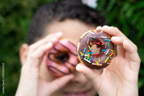 Hand Holding Chocolate Sprinkle Donut Against Neutral Background