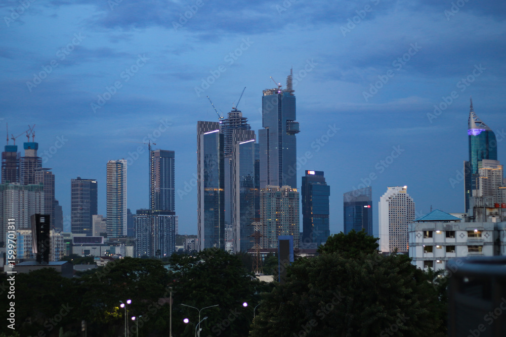 Obraz premium A high resolution image of modern skyscrapers and office towers in Jakarta central business district, Indonesia. The photo showcases glass covered buildings under a dramatic cloudy sky, representing t